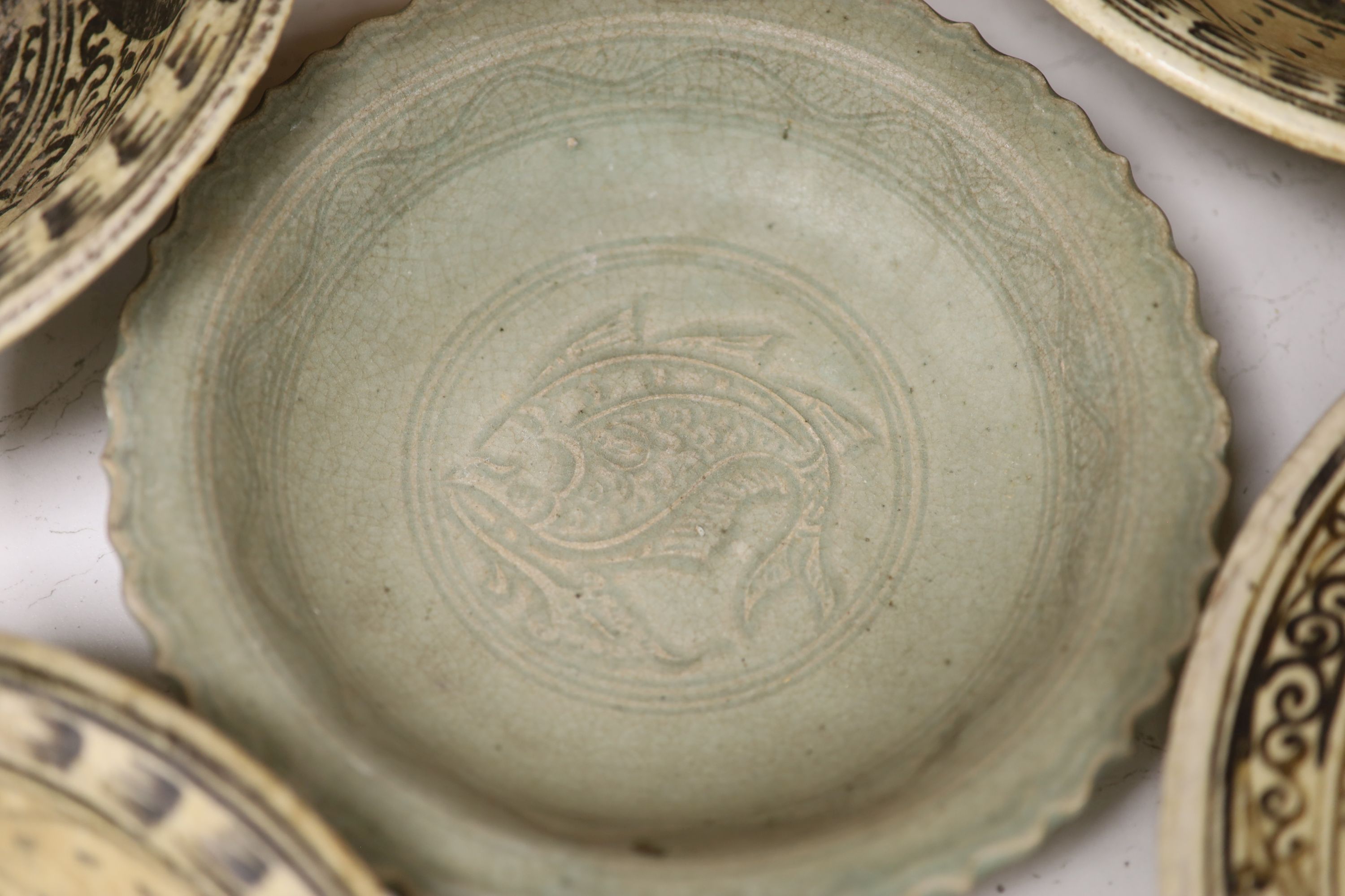 Four Sukhothai style dishes and a Thai celadon dish, diameter 32cm